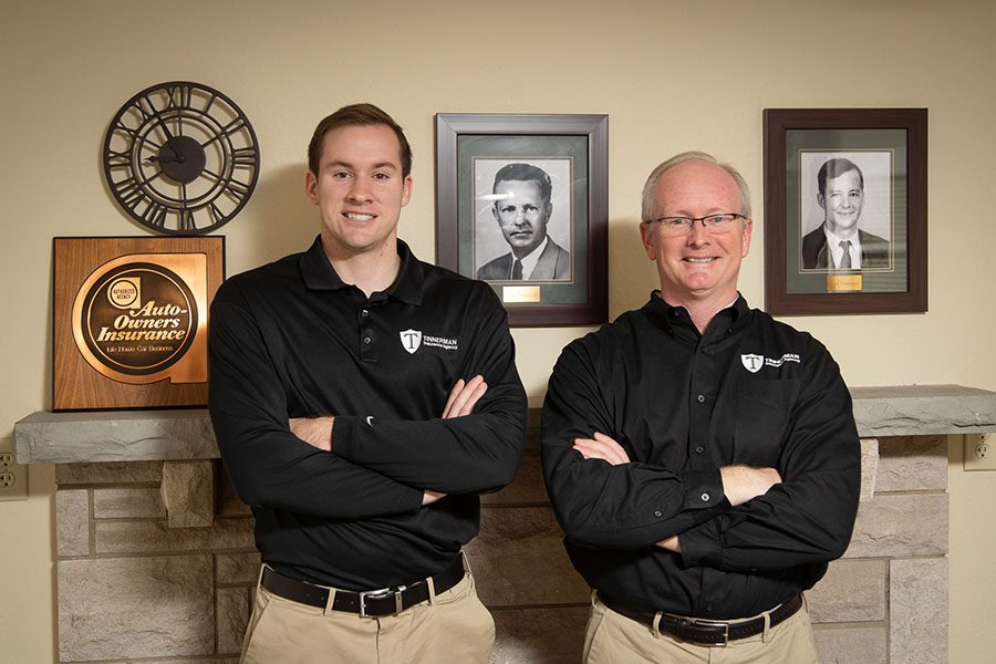 About Our Agency - Portrait of Ron and Grant Tinnerman Standing in the Tinnerman Insurance Agency Office with Old Photos of Family in the Background